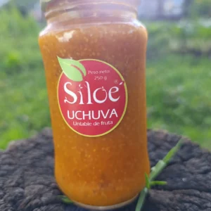 Frasco de mermelada artesanal de uchuva con semillas de chía sobre tronco natural
