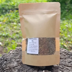 Bolsa ecológica de hierbabuena molida sobre tronco de madera en entorno natural.