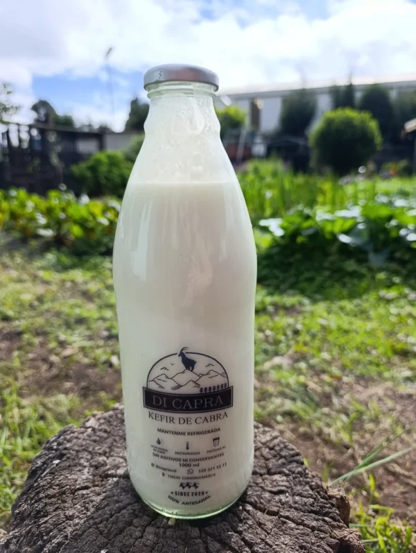 Botella de kéfir de cabra artesanal sobre tronco en ambiente verde.