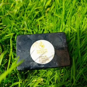 Jabón artesanal negro de carbón activado Rosemary Herbal sobre césped verde.