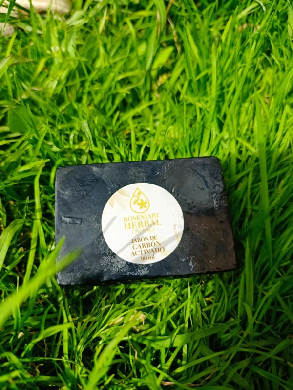 Jabón artesanal negro de carbón activado Rosemary Herbal sobre césped verde.