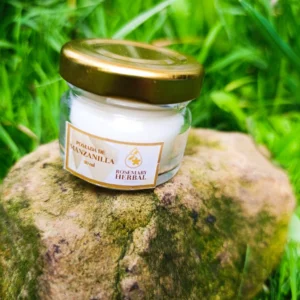 Frasco de pomada de manzanilla Rosemary Herbal de 30 ml sobre piedra, con fondo de pasto verde.